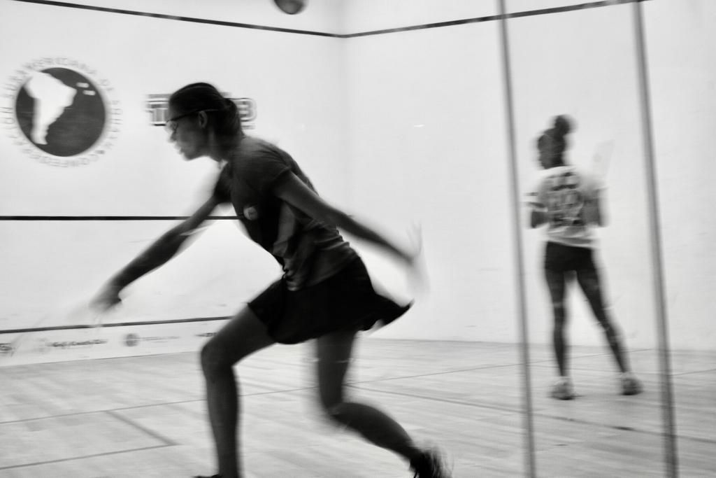 Duas mulheres estão jogando squash em uma foto em preto e branco.