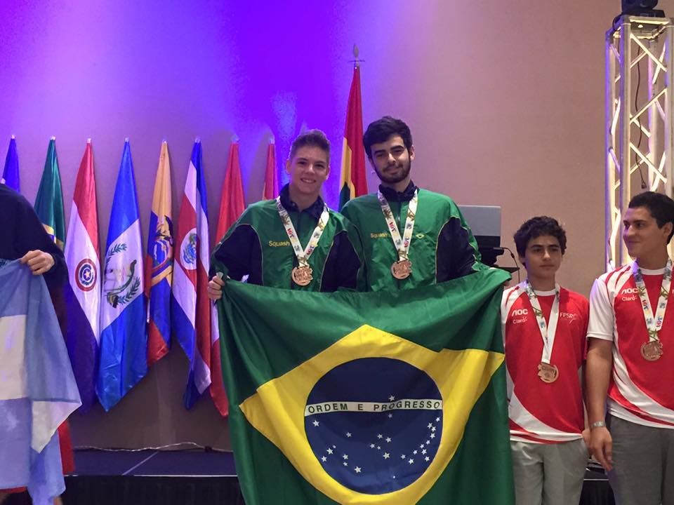 um grupo de jovens parados um ao lado do outro segurando uma bandeira brasileira.
