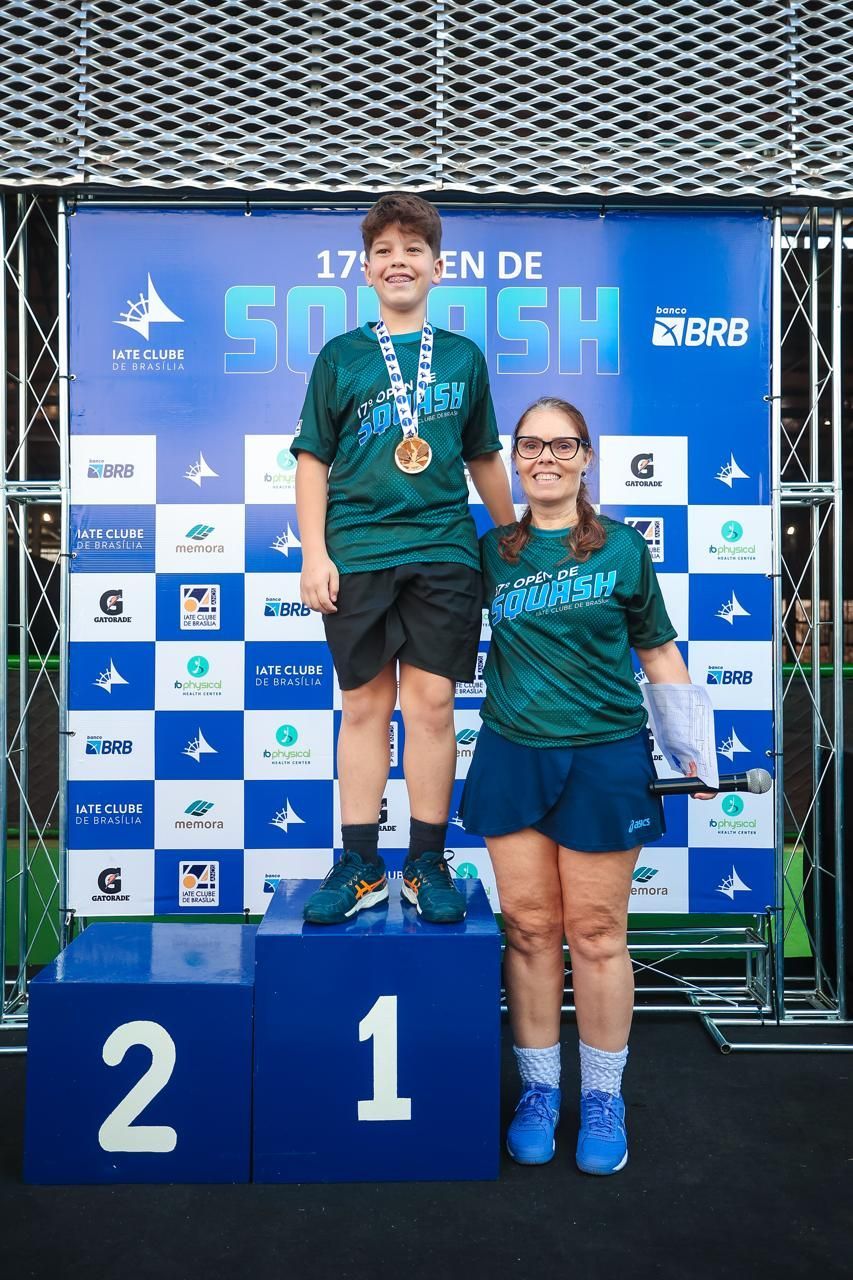 Duas pessoas em pé em um pódio com o número 2 nele