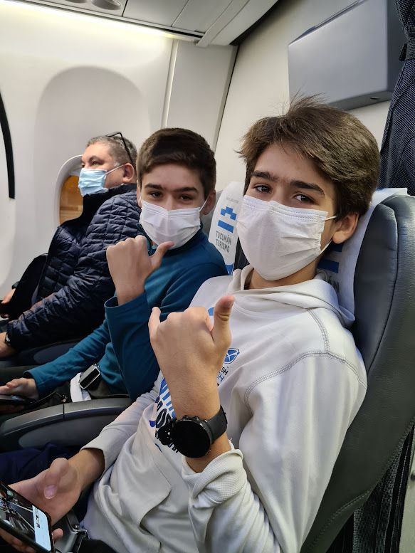 Um grupo de jovens usando máscaras faciais estão sentados em um avião.