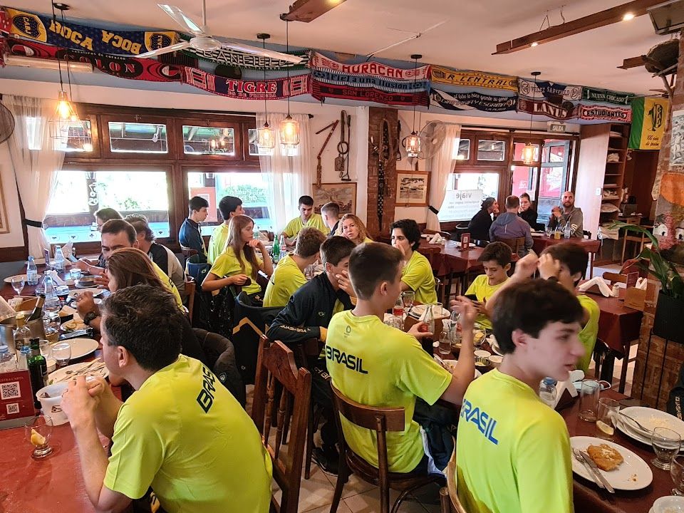 Um grupo de pessoas com camisas amarelas estão sentadas em mesas em um restaurante.