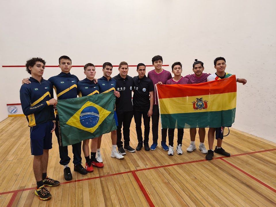 um grupo de jovens está em pé sobre um chão de madeira segurando bandeiras.
