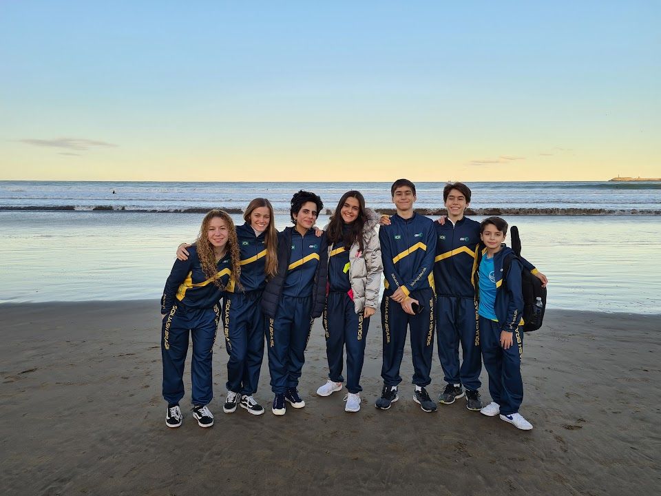 Um grupo de jovens está posando para uma foto na praia.
