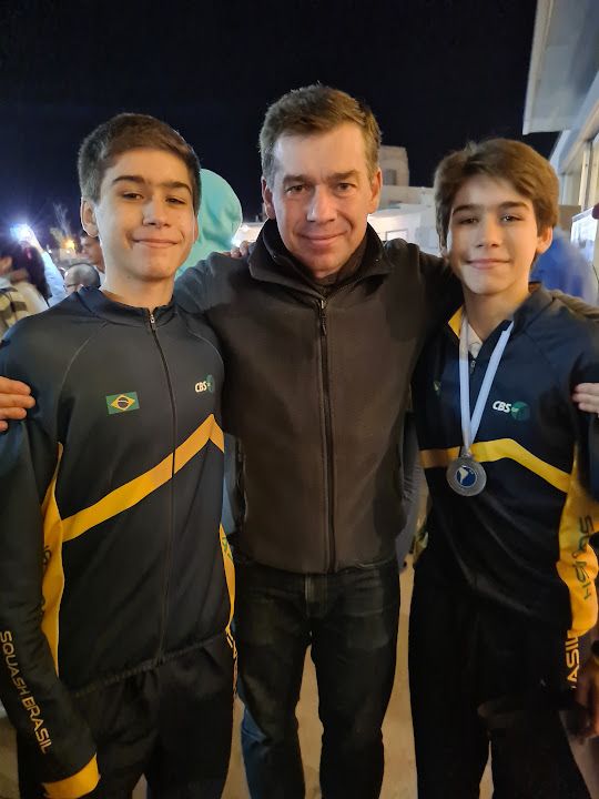 Um homem está posando para uma foto com dois meninos usando medalhas