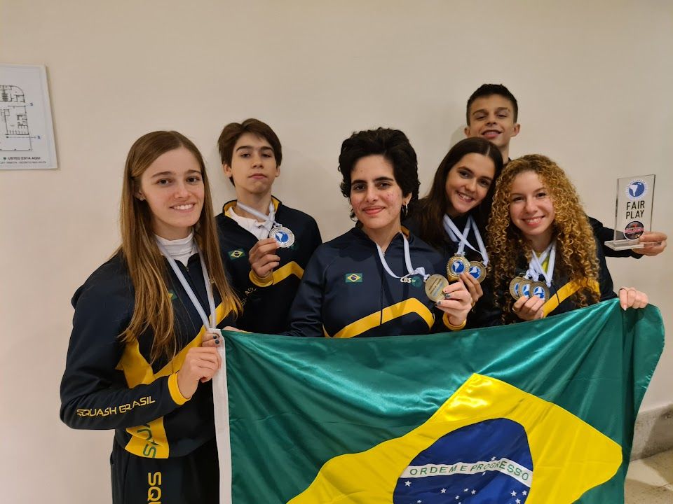 um grupo de pessoas segurando medalhas e uma bandeira