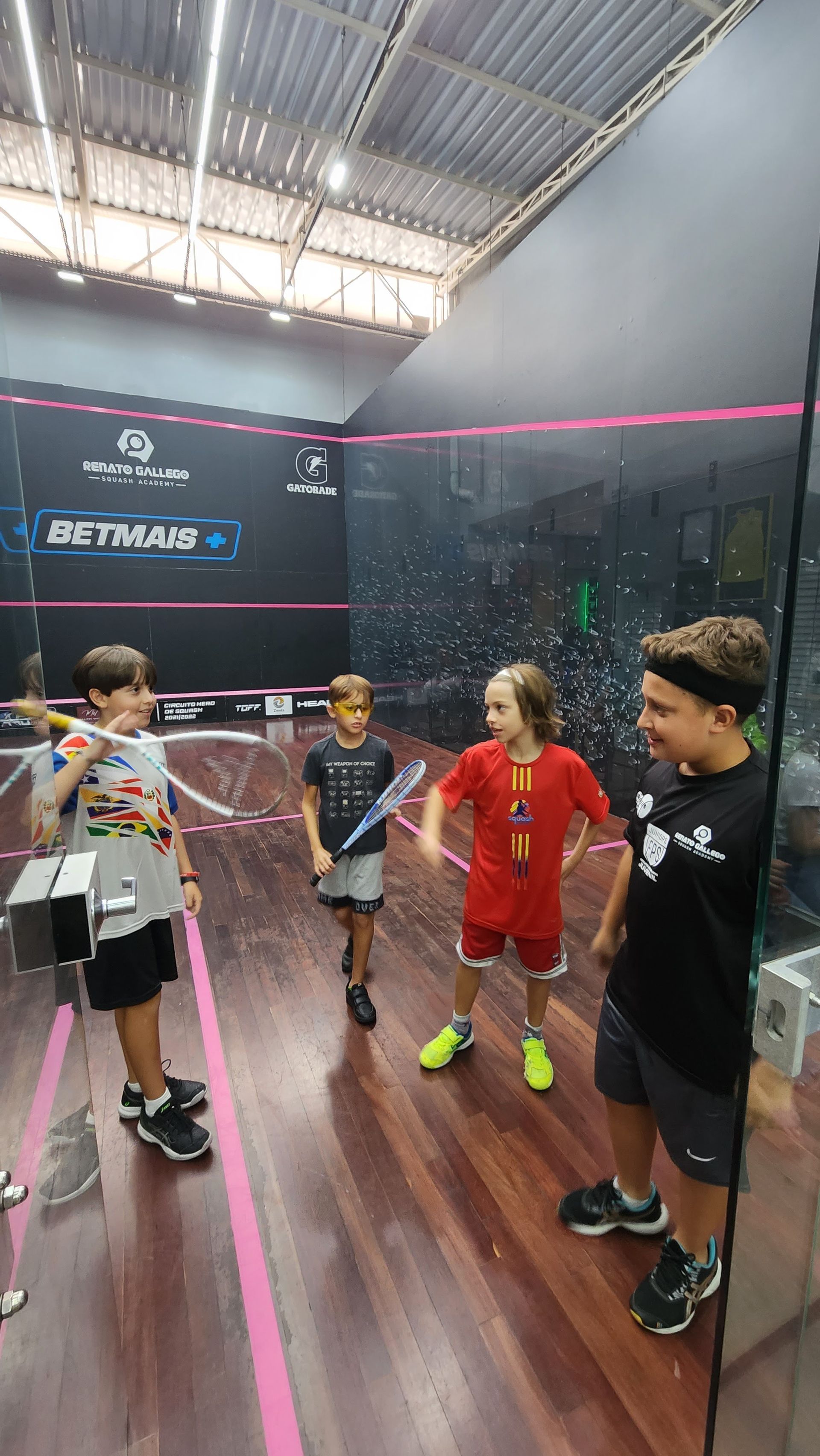 Um grupo de meninos está em uma quadra de squash.