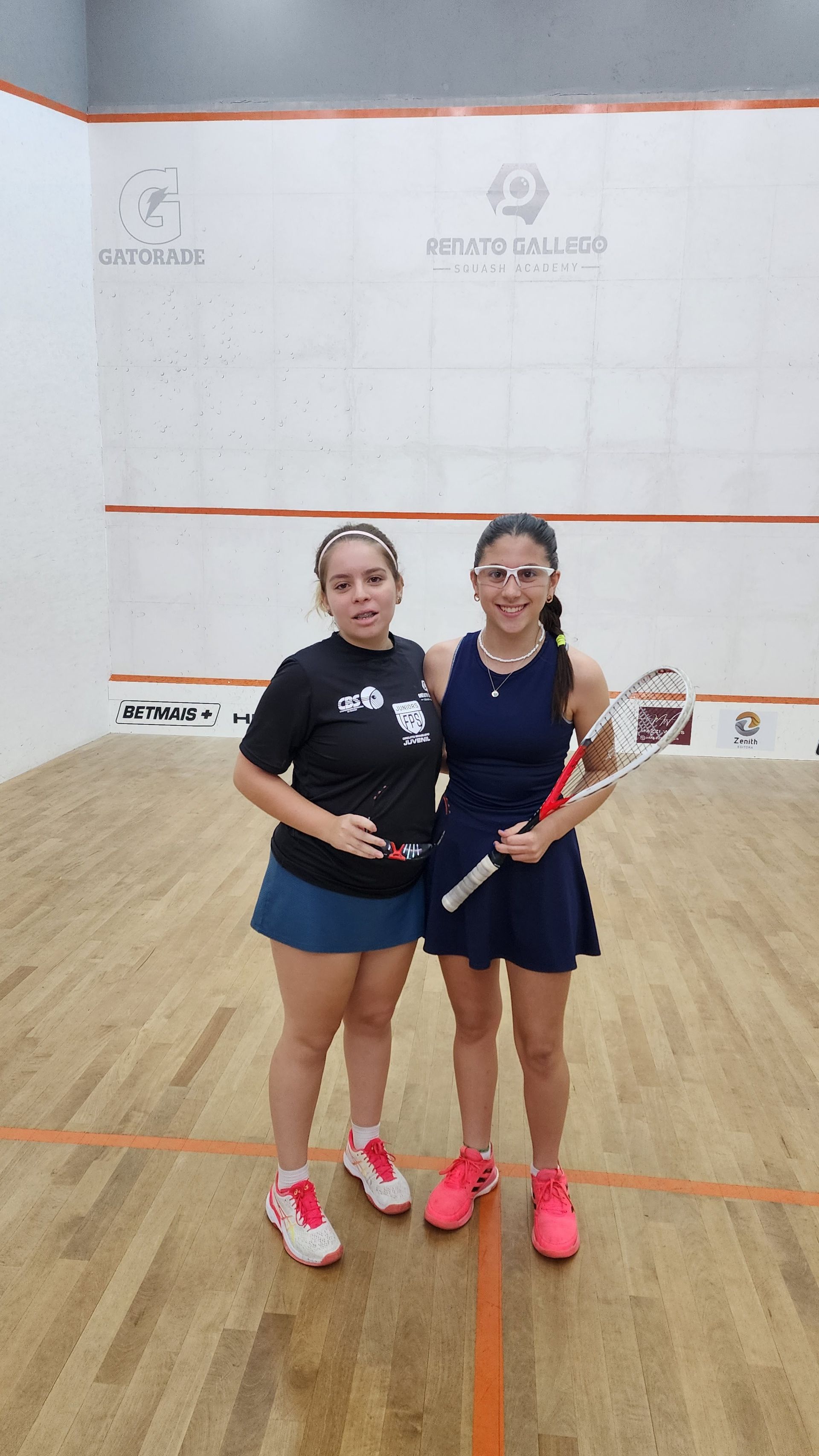 Duas mulheres estão posando para uma foto em uma quadra de squash.