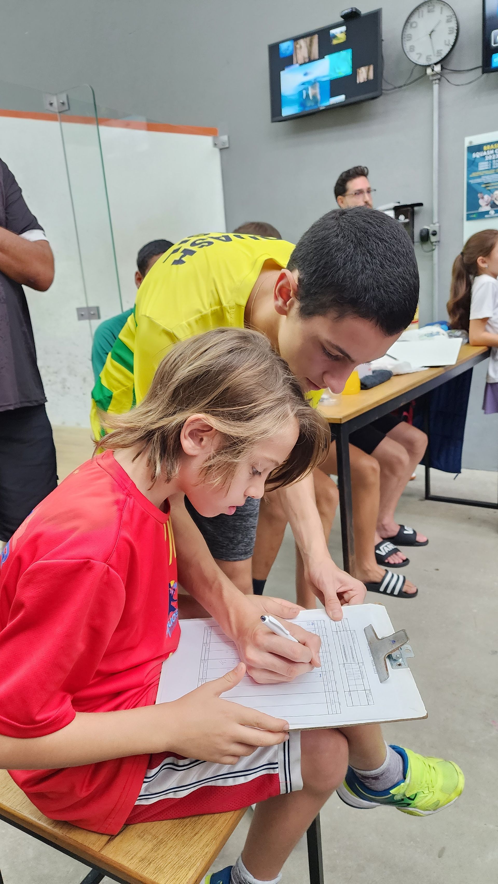 um homem e um menino estão sentados em um banco escrevendo em um pedaço de papel.
