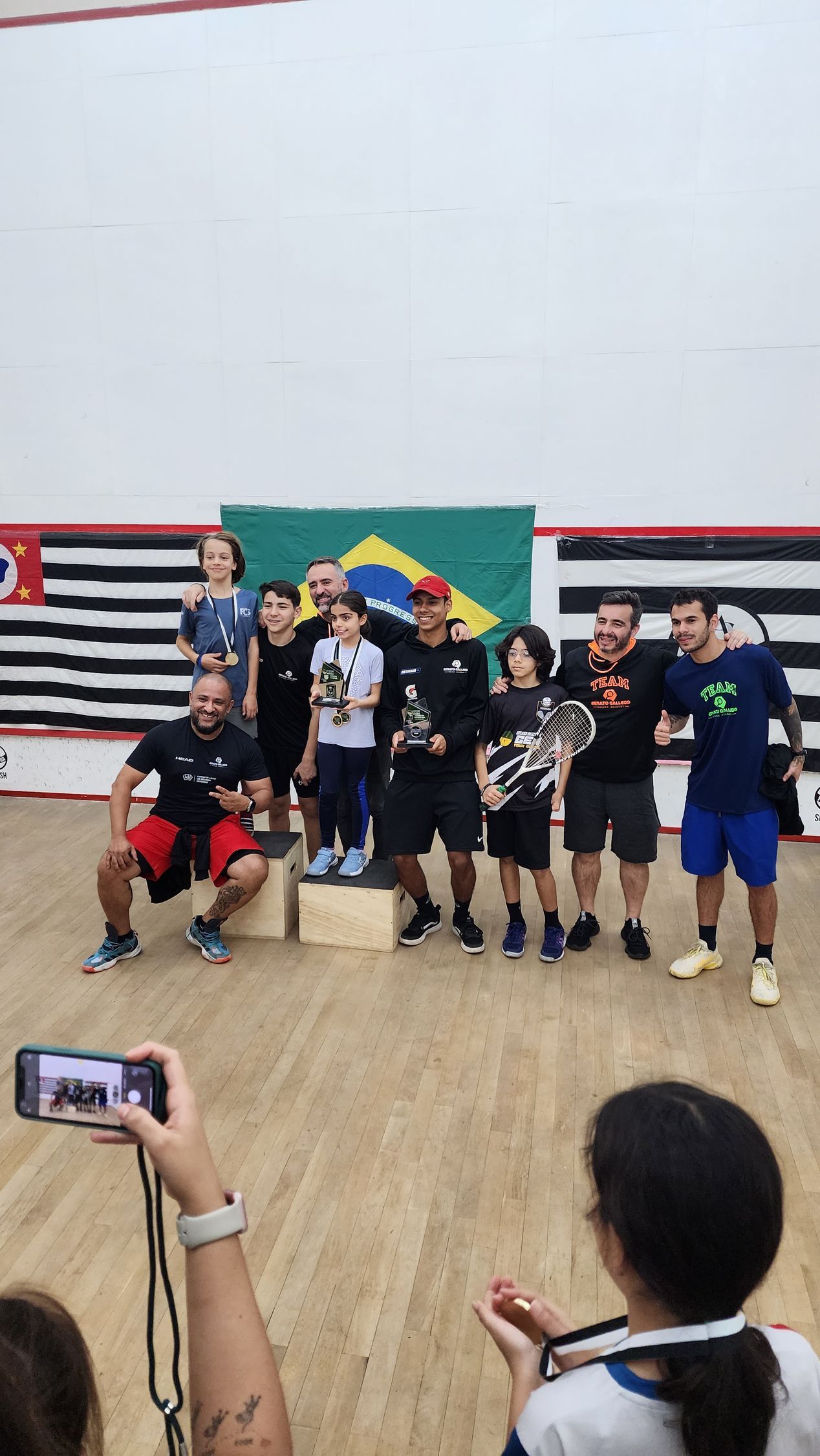 Uma mulher está tirando uma foto de um grupo de pessoas em pé em um pódio.
