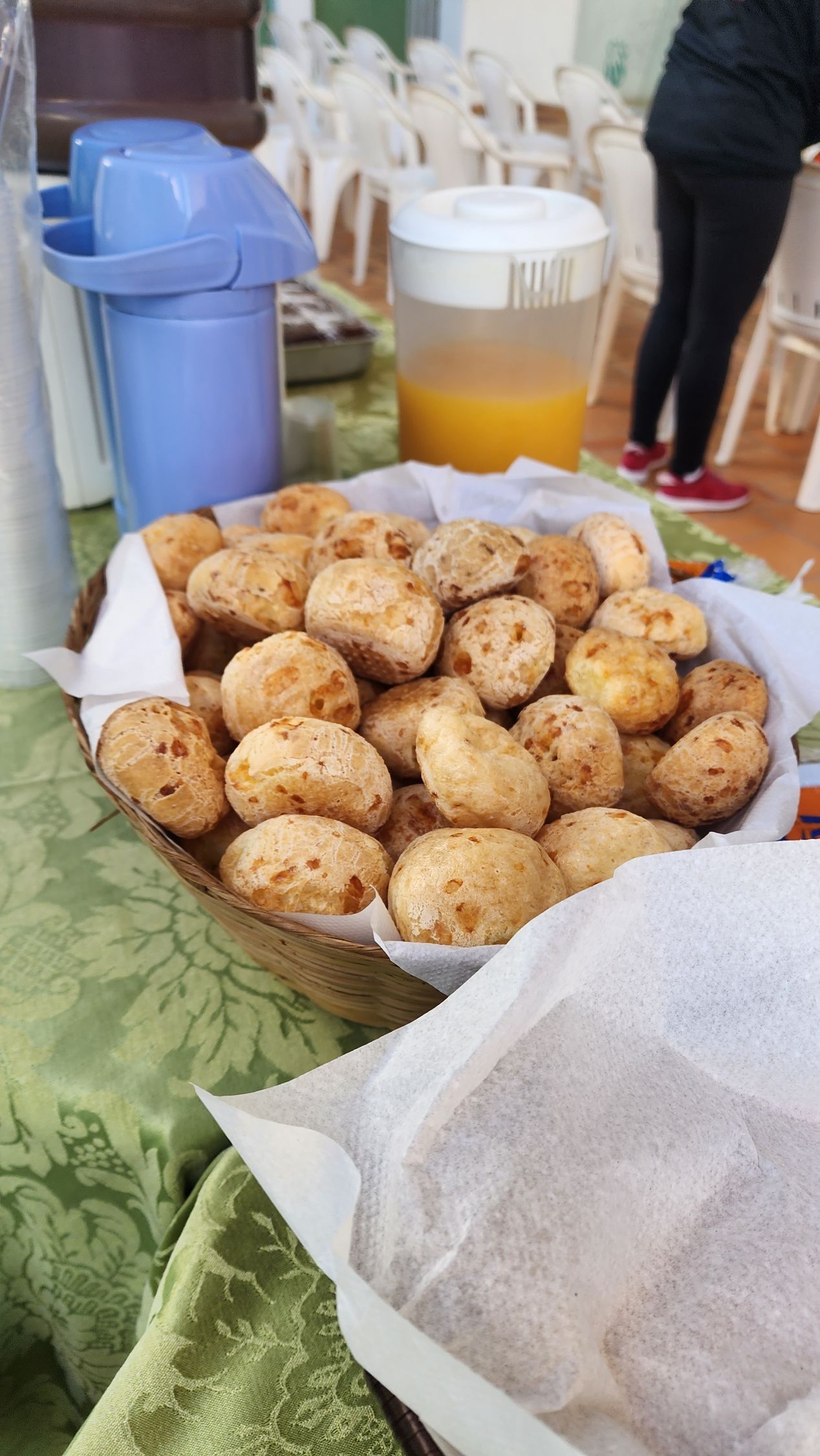 uma cesta de comida está sobre uma mesa ao lado de uma jarra de suco de laranja.