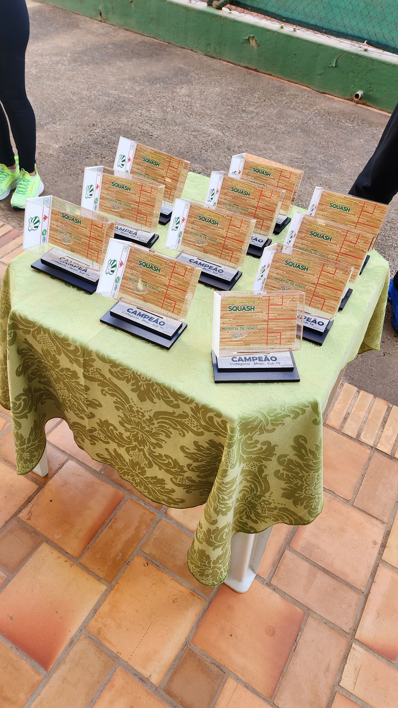 uma mesa com uma toalha verde e um monte de troféus.