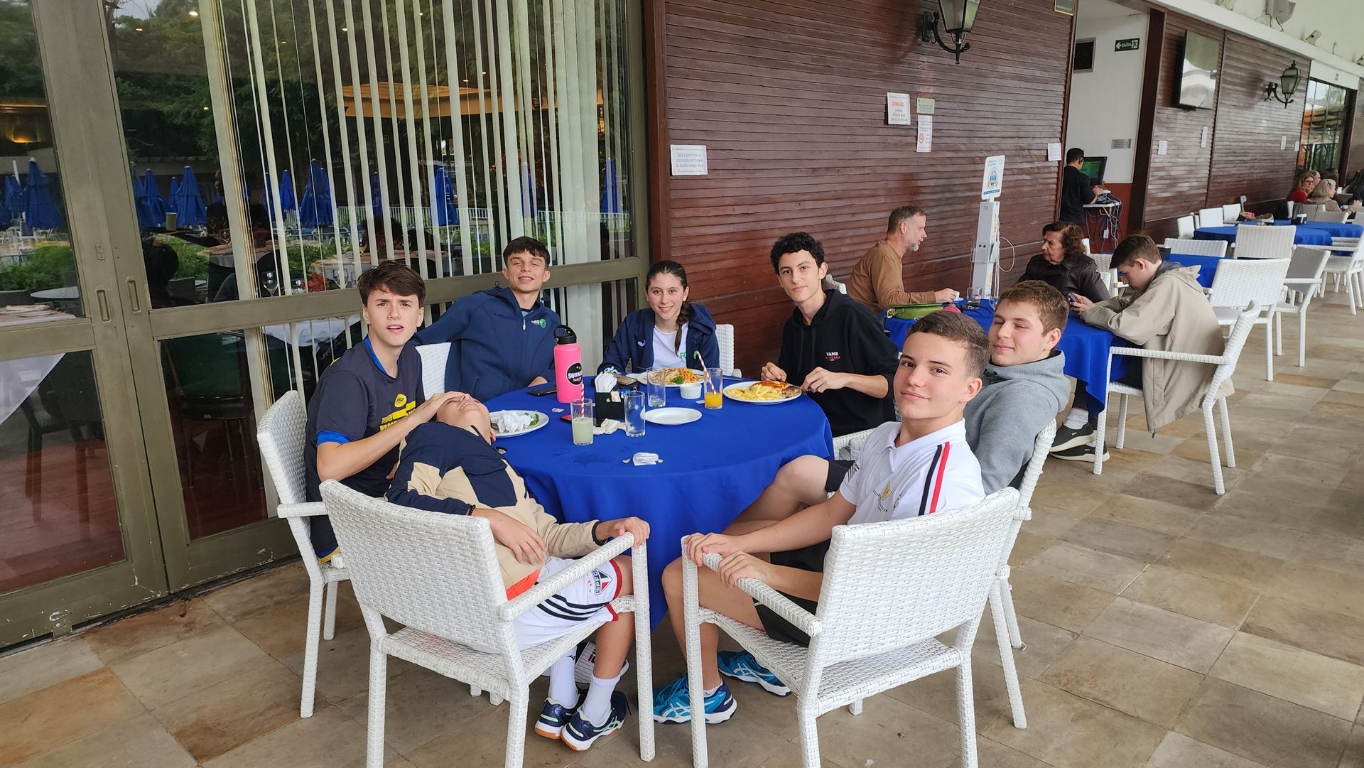 Um grupo de pessoas está sentado ao redor de uma mesa comendo.