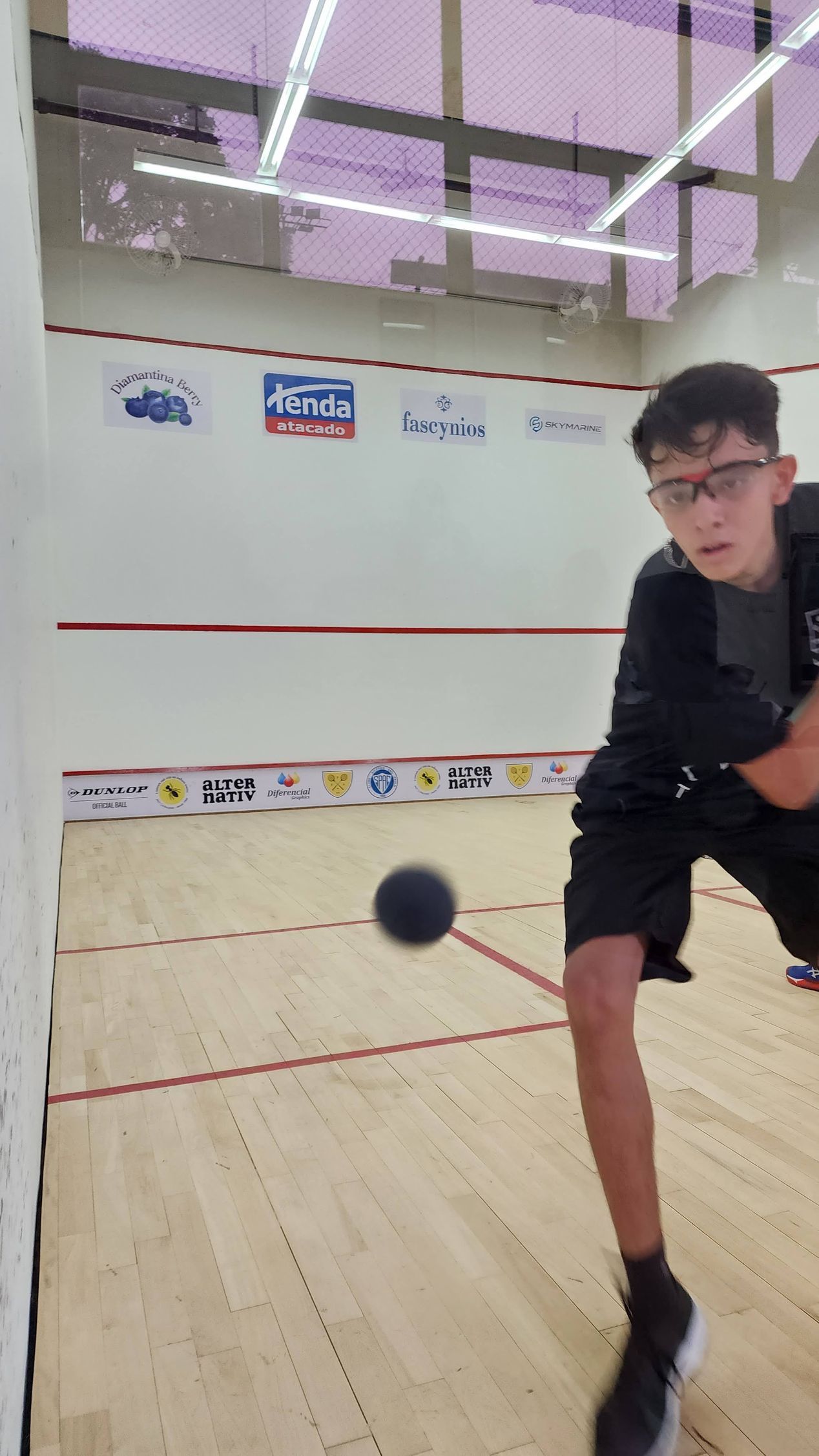 Um jovem está jogando squash em uma quadra.