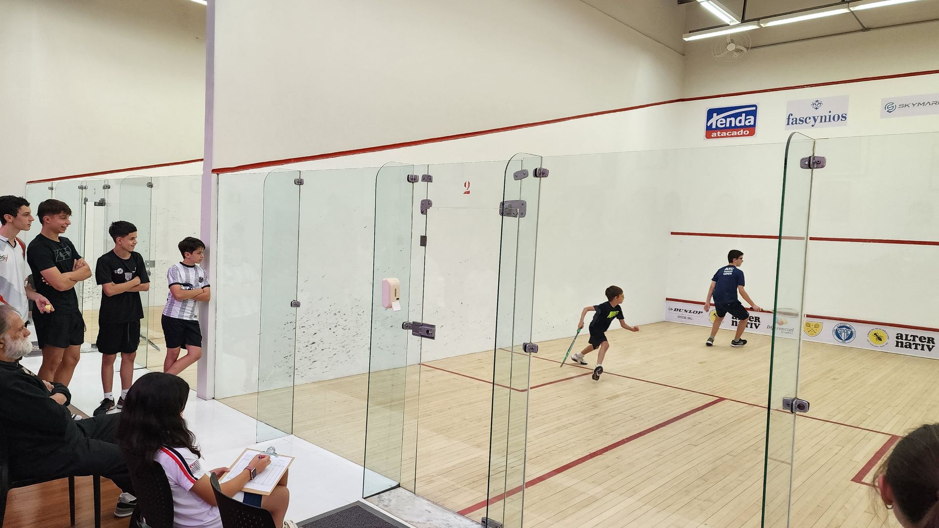 Um grupo de pessoas está jogando squash em uma quadra.