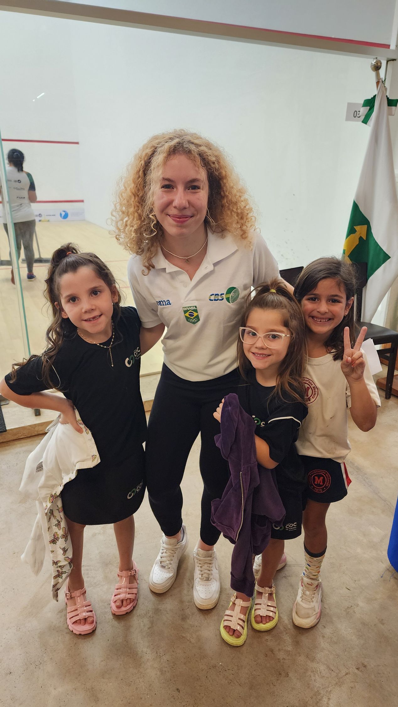 uma mulher posa para uma foto com três meninas.
