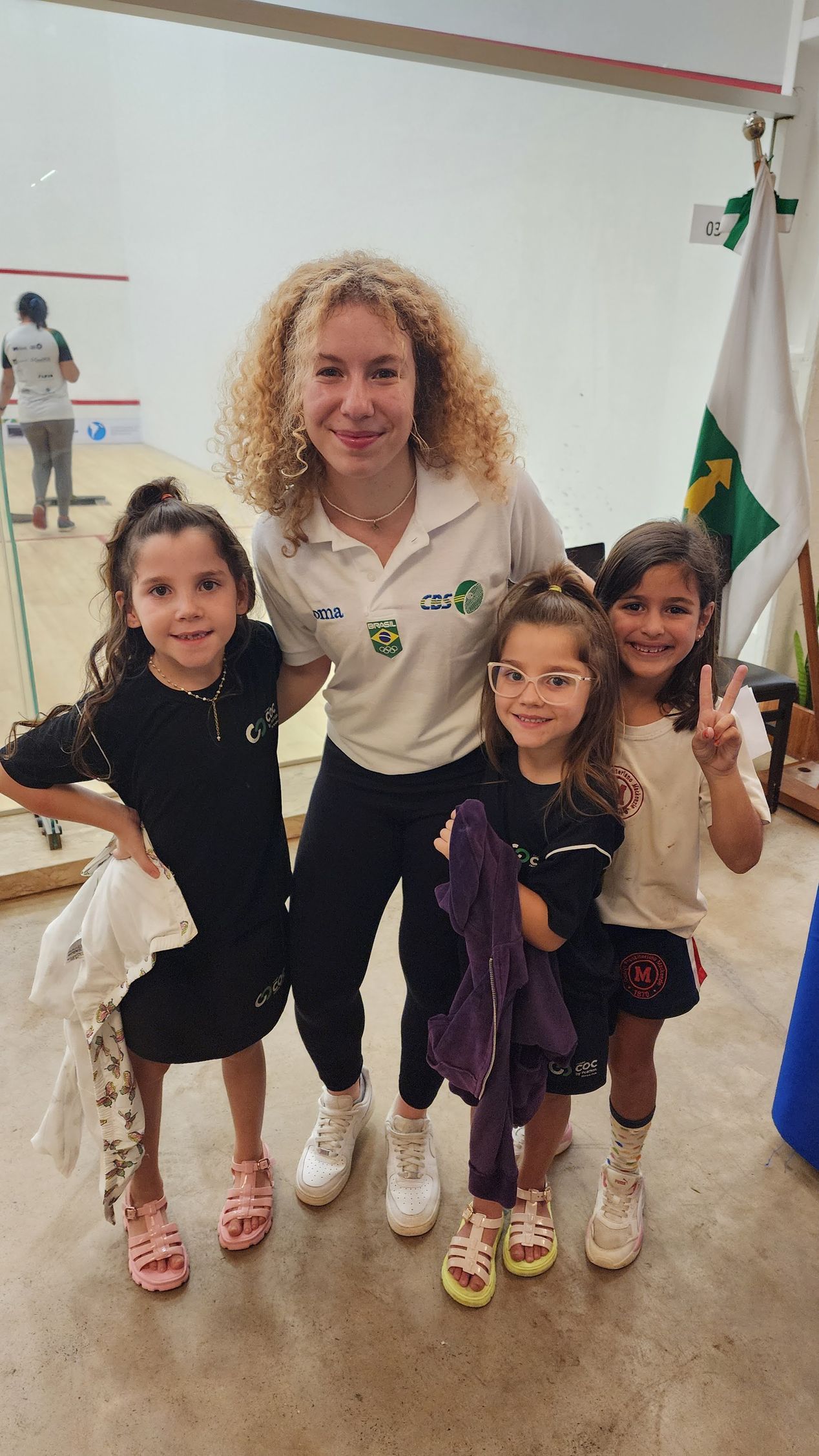 uma mulher posa para uma foto com três meninas.