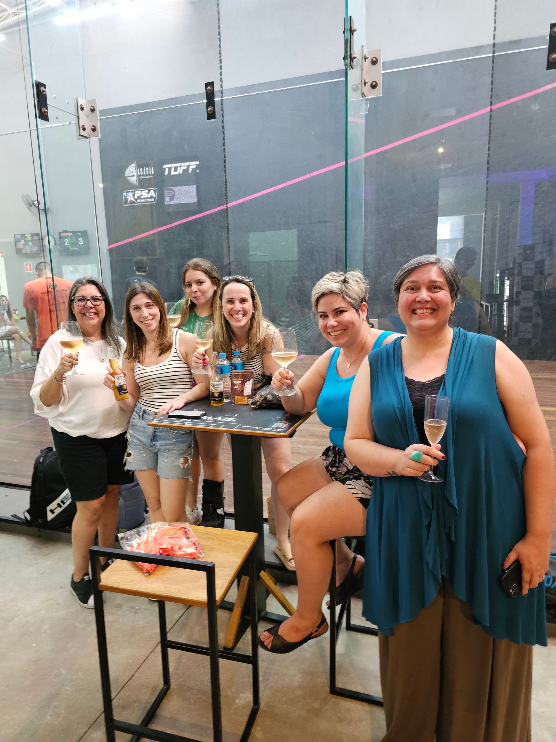 Um grupo de mulheres está sentado à mesa segurando taças de champanhe.