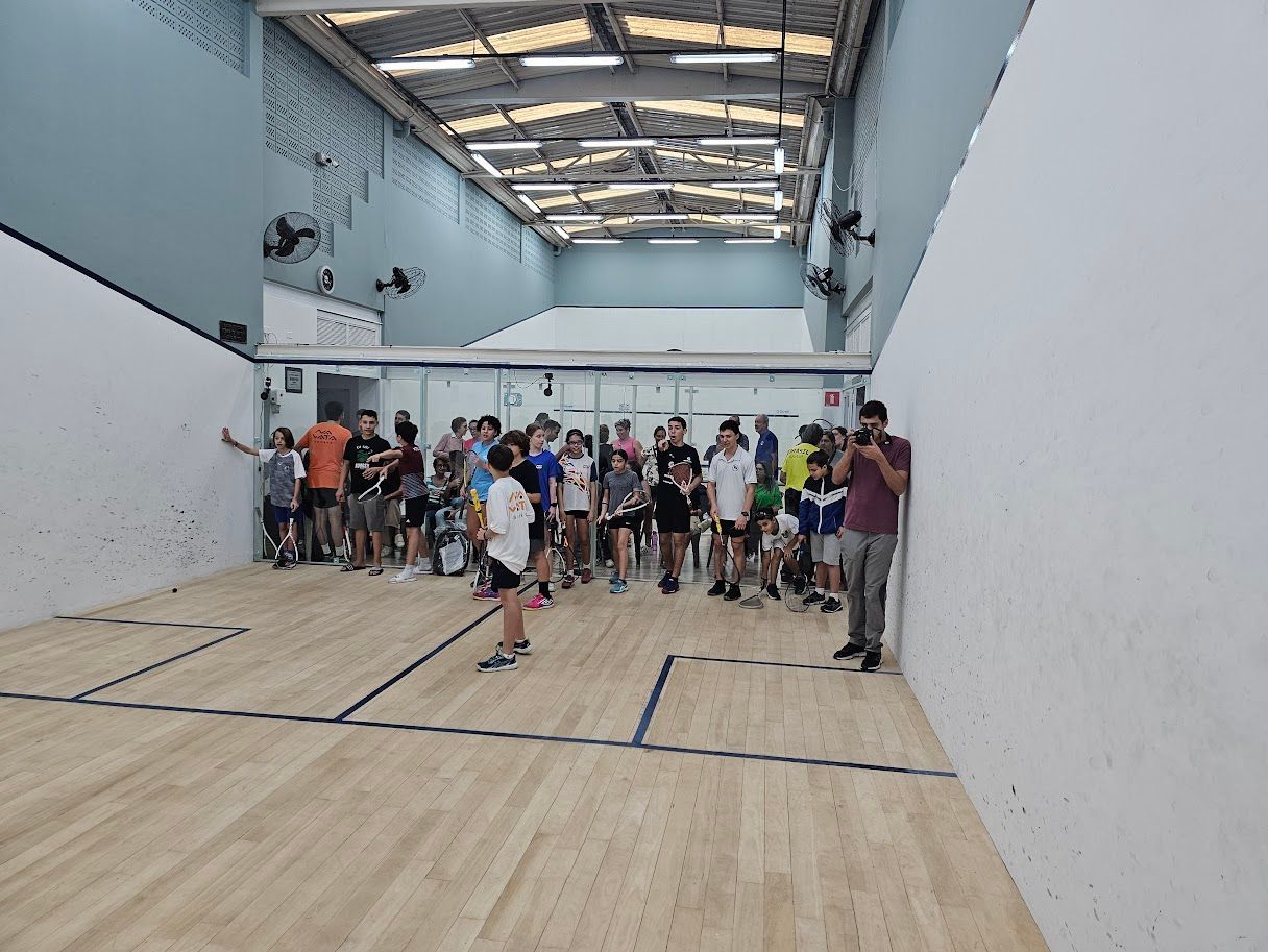 Um grupo de pessoas está em uma quadra de squash.