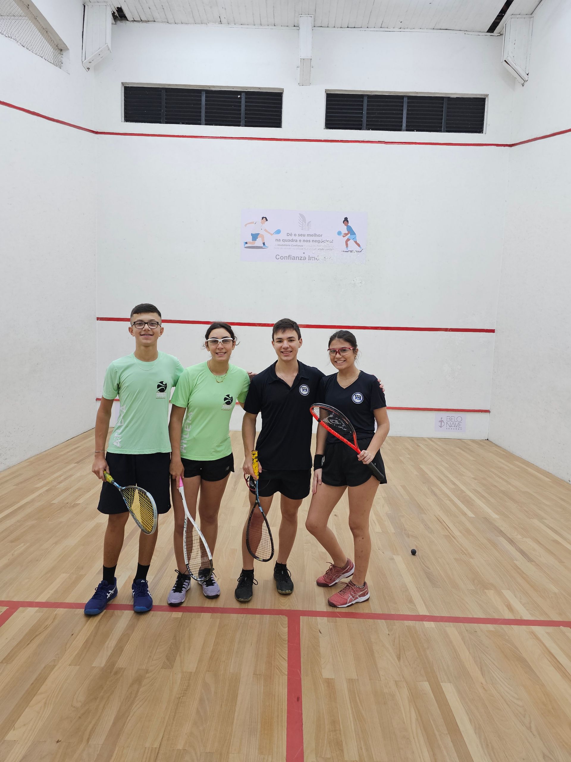 Um grupo de pessoas está posando para uma foto em uma quadra de squash