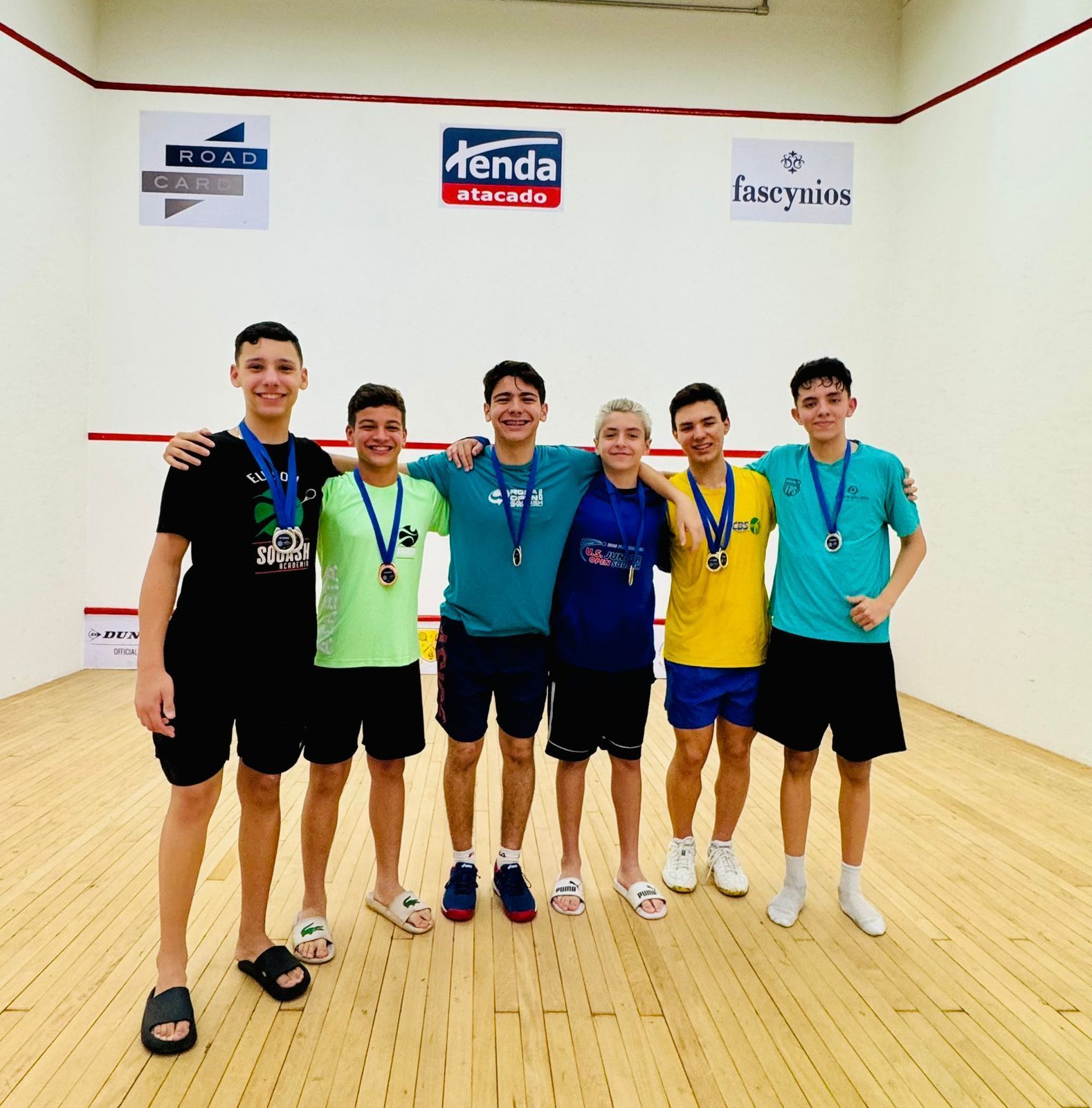 Um grupo de jovens posando para uma foto com medalhas penduradas no pescoço