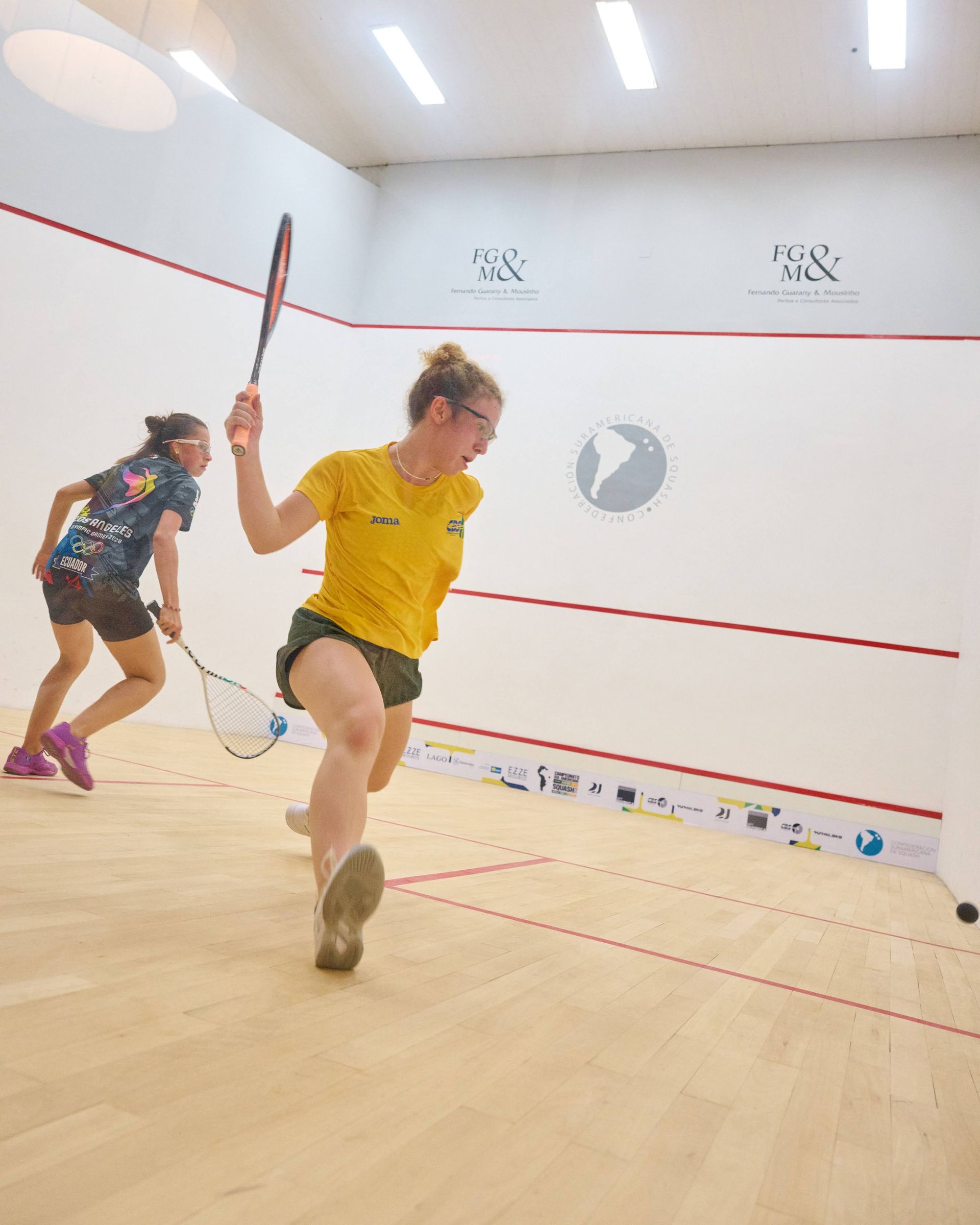 duas mulheres estão jogando squash em uma quadra.