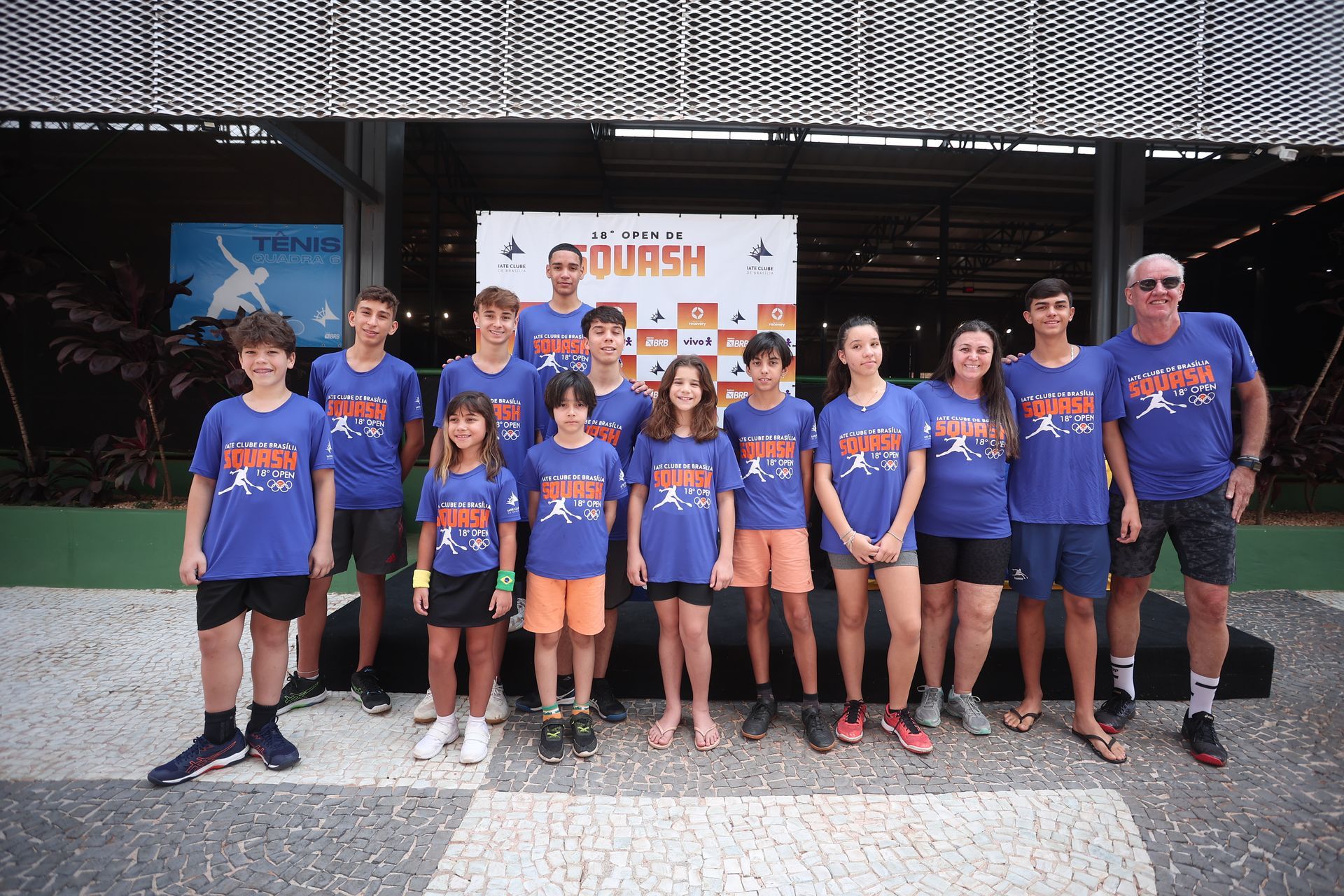 Um grupo de pessoas em pé na frente de uma placa que diz squash