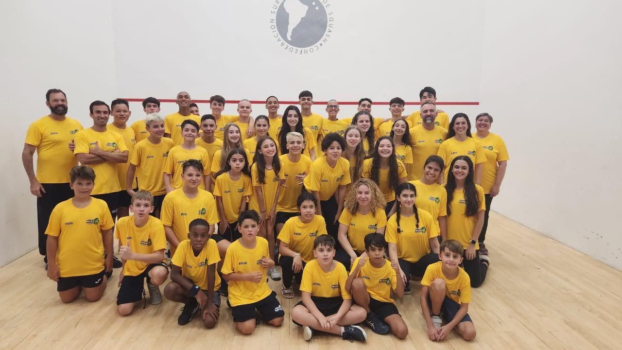 um grande grupo de pessoas vestindo camisas amarelas posa para uma foto.