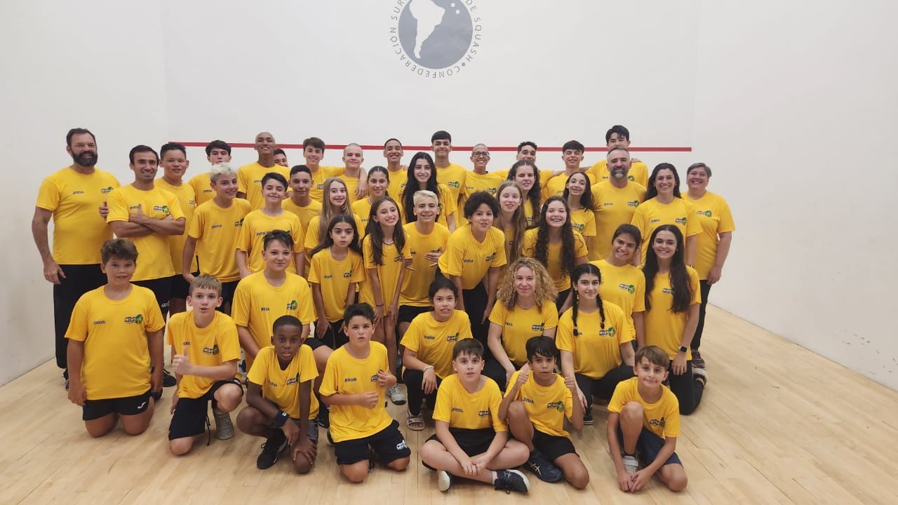 um grande grupo de pessoas vestindo camisas amarelas posa para uma foto.
