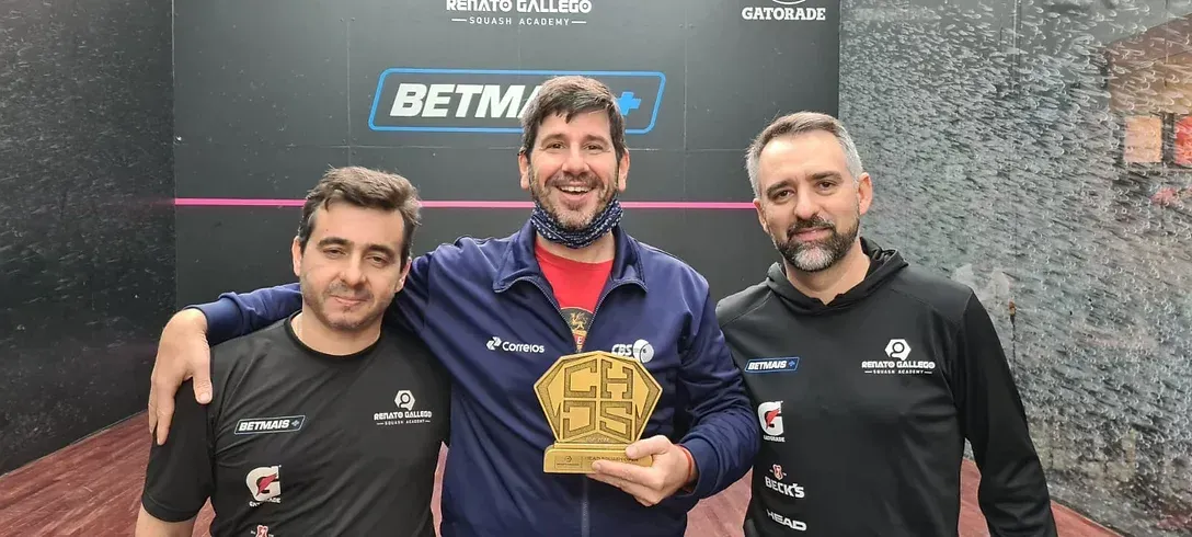 Três homens estão posando para uma foto enquanto um deles segura um troféu.