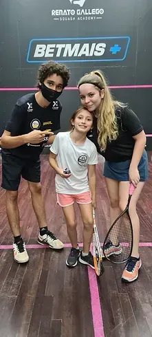Um grupo de pessoas está posando para uma foto em uma quadra de squash.