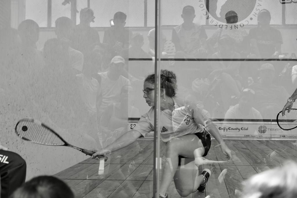 Uma mulher está jogando squash em uma foto em preto e branco.