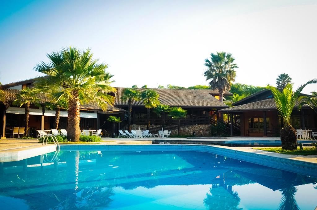 Uma grande piscina em frente a uma casa com palmeiras