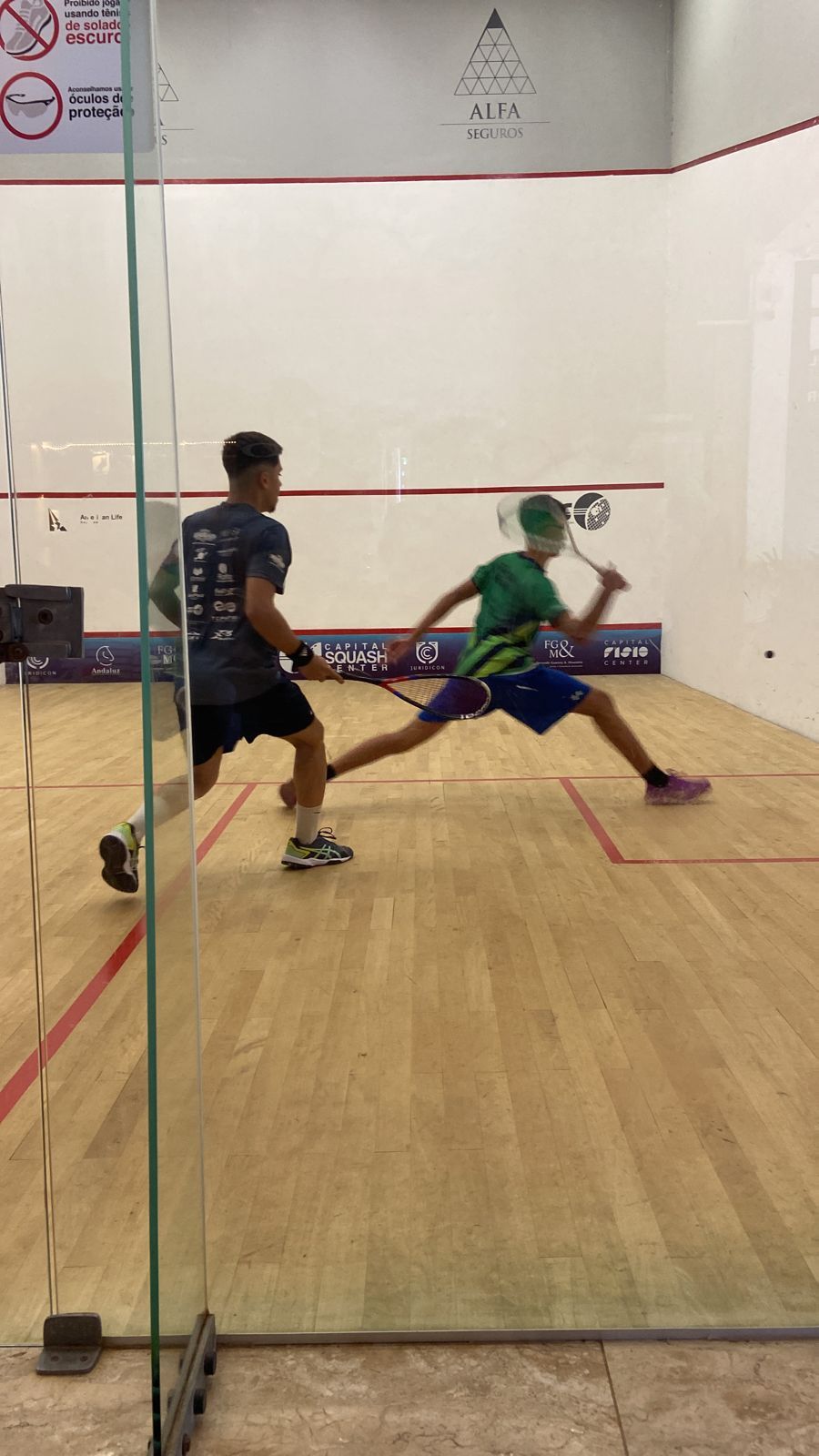 Dois homens estão jogando squash em uma quadra.