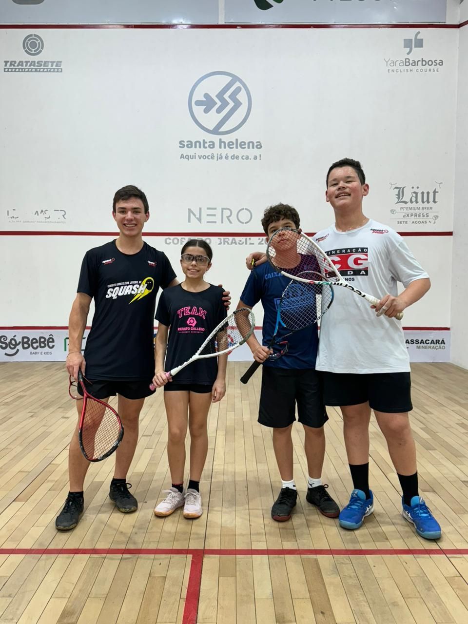 Um grupo de jovens está posando para uma foto em uma quadra de squash