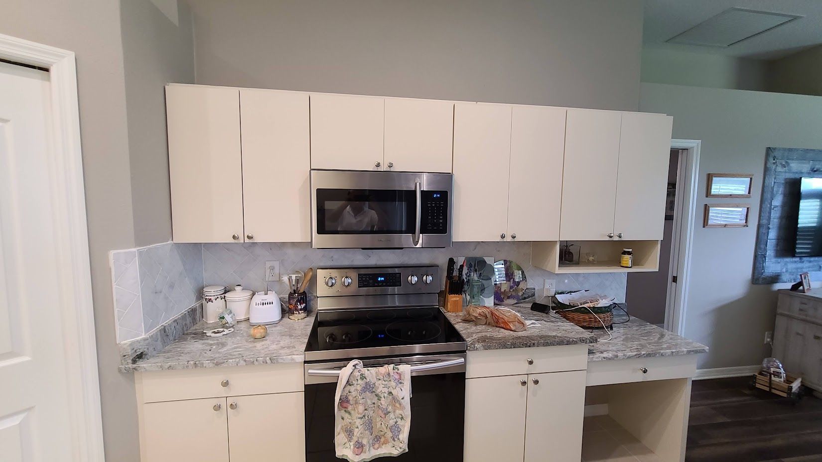 A kitchen with white cabinets , stainless steel appliances , and granite counter tops.