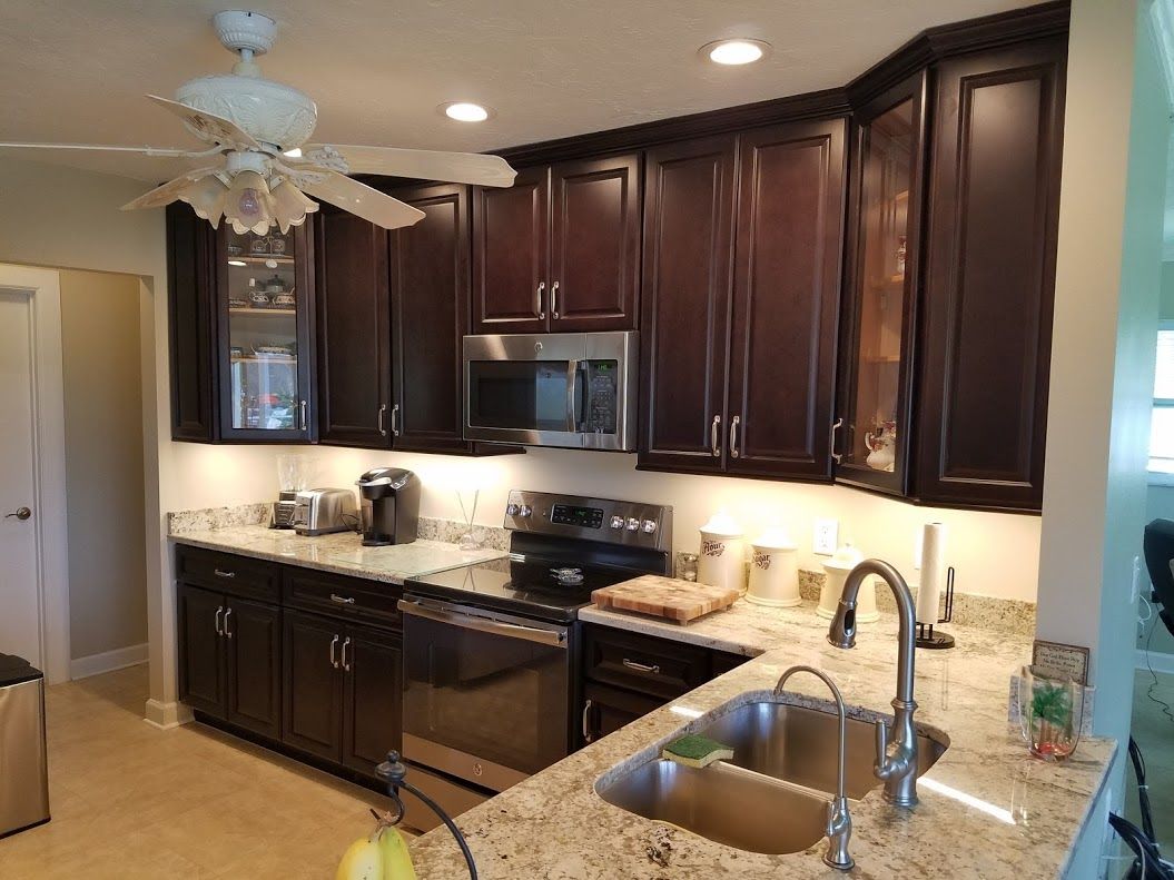 A kitchen with stainless steel appliances , granite counter tops , a sink and a ceiling fan.