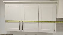 A measuring tape is being used to measure the height of a cabinet