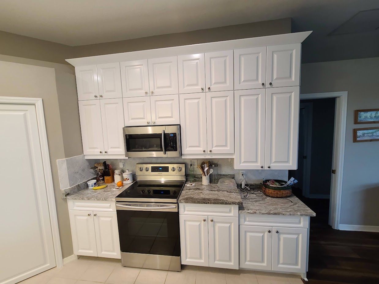 A kitchen with white cabinets , stainless steel appliances , and granite counter tops.