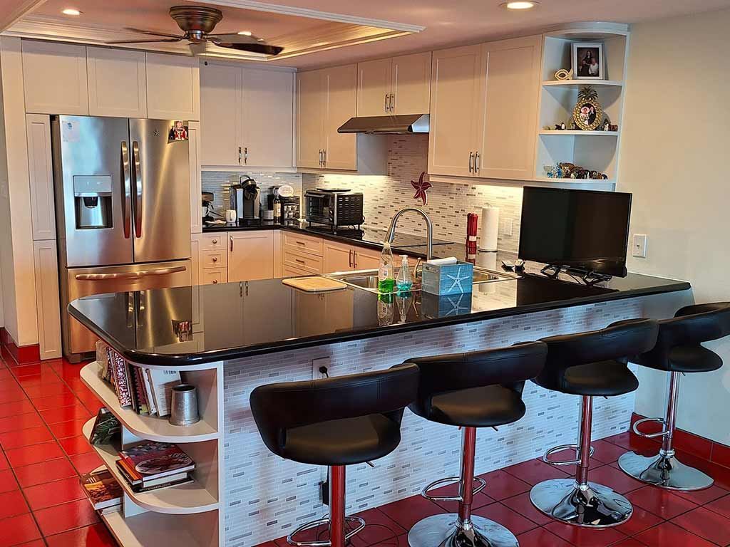 A kitchen with stools , a refrigerator , and a computer on the counter.