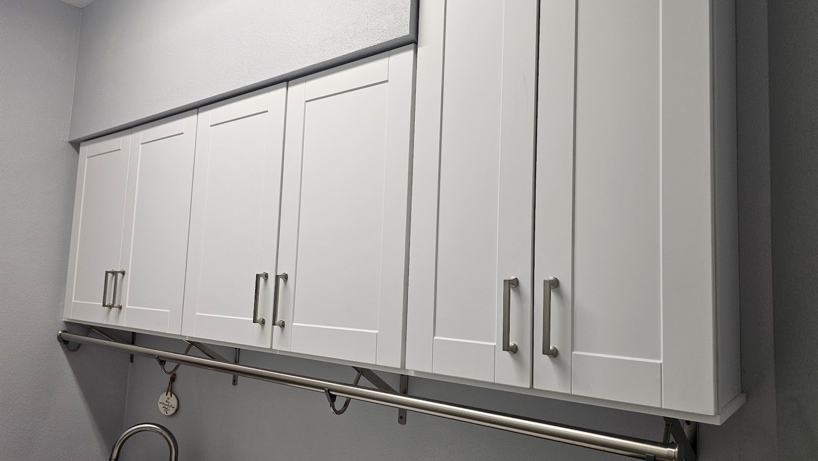 A laundry room with white cabinets and a sink.