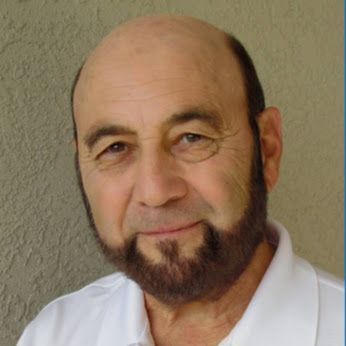 A bald man with a beard wearing a white shirt