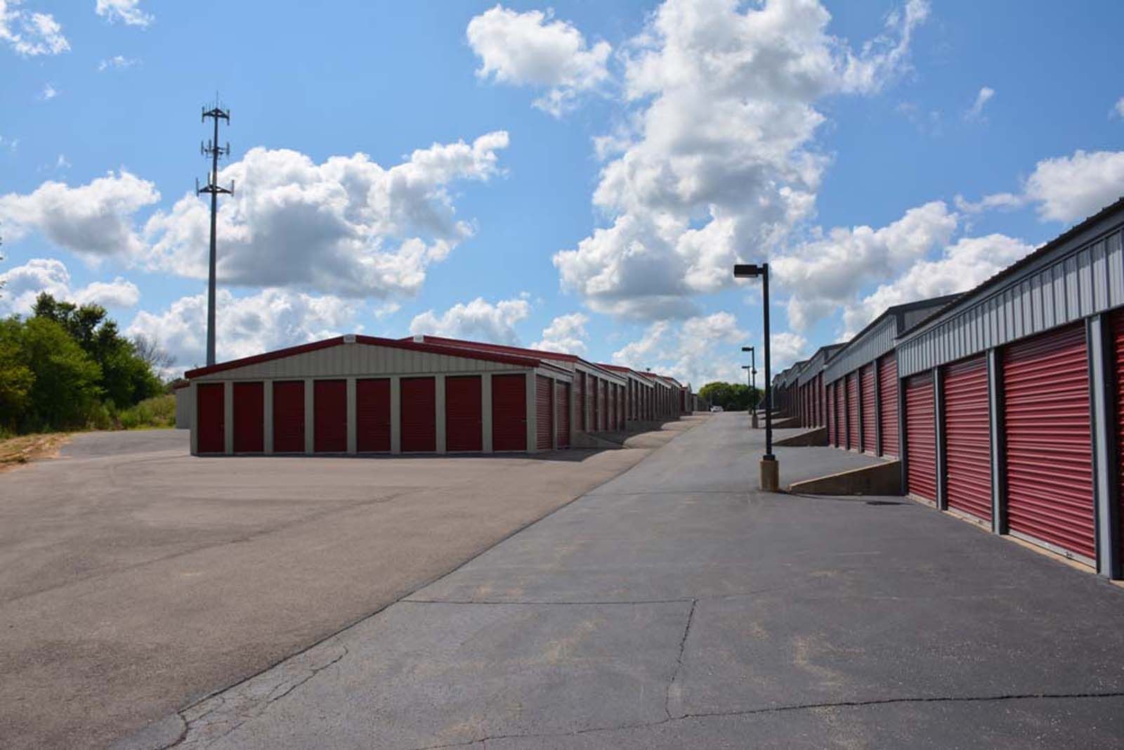 Storage unit facility with rows of red garage doors on a sunny day