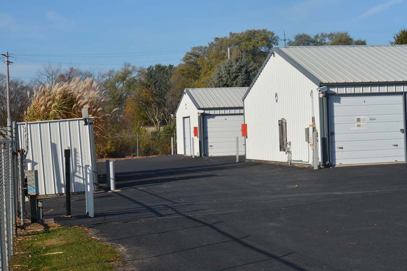 Row of white industrial storage units beside a paved lot under a clear sky