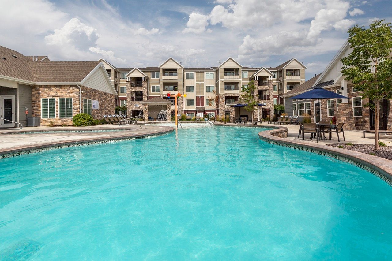 Outdoor pool at an apartment community with lounge chairs and surrounding buildings at Herriman Towne Center in Herriman, UT.
