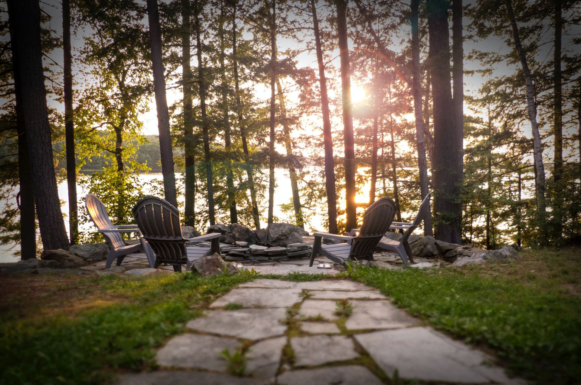 A stone walkway leading to a fire pit in the middle of a forest.