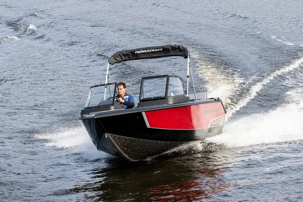 A man is driving a boat on a lake.