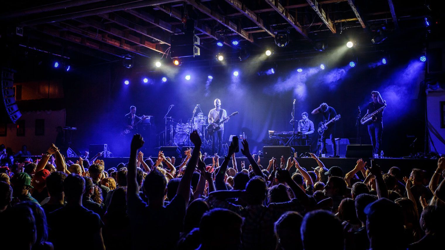 A crowd of people are standing in front of a stage at a concert.