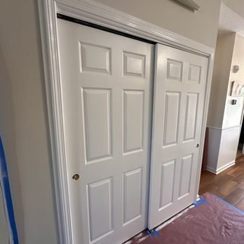 White, six-panel sliding closet doors with black top rail, against a white wall.