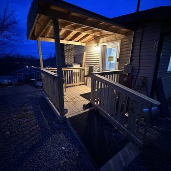 Wooden porch and ramp, illuminated at dusk, leading to a building's entrance.