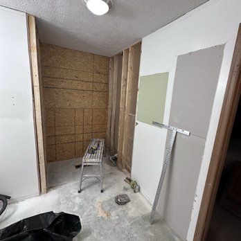 Bathroom under renovation, studs and OSB visible. Light fixture, paint swatches, and a step stool present.